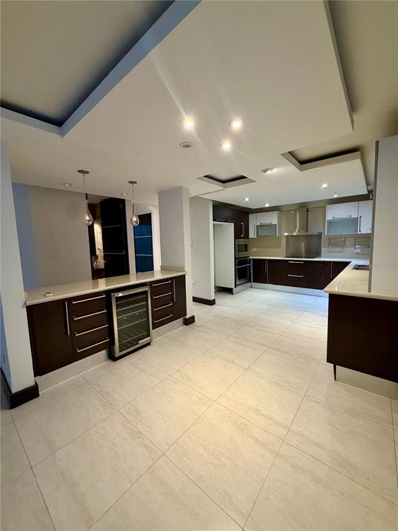 A modern kitchen features dark wood cabinetry, white countertops, a wine cooler, and tile flooring — 366 LOS ARBOLES DE MONTEHIDRA, SAN JUAN, PR