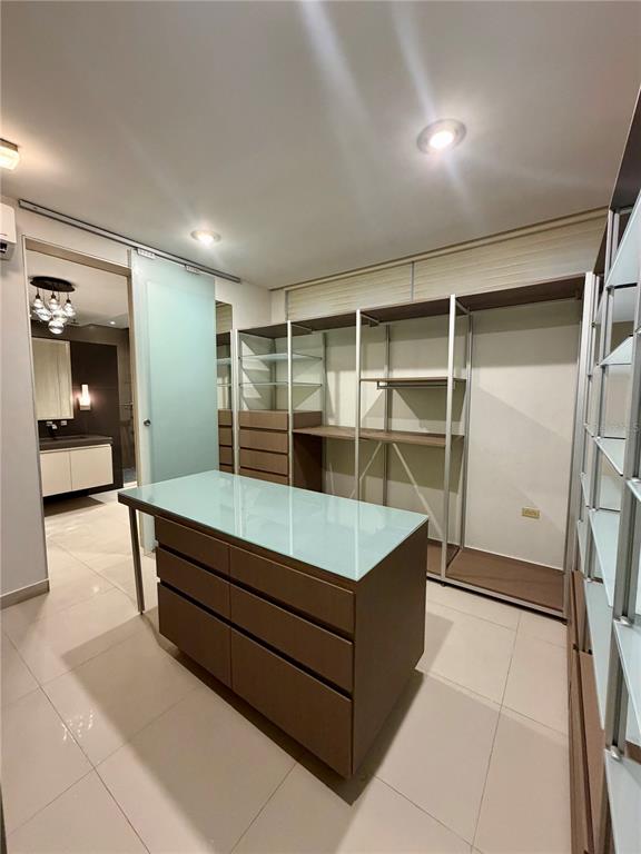 A walk-in closet features a central island with a glass top and open shelving units — 366 LOS ARBOLES DE MONTEHIDRA, SAN JUAN, PR