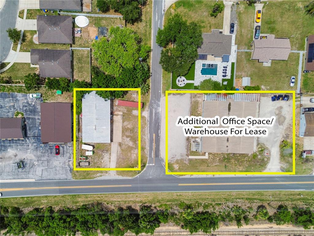 This aerial view shows two commercial properties with buildings and parking lots along a road — 15601 OLD US HIGHWAY 441, TAVARES, FL