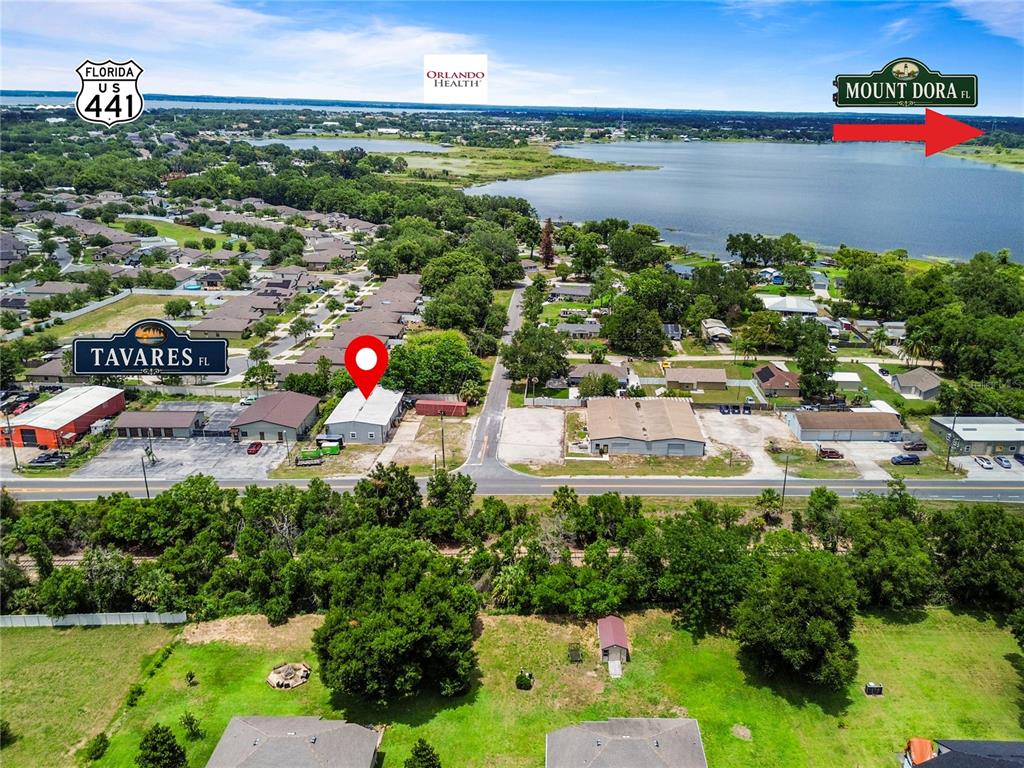 This aerial view shows a commercial building with a red location pin near a lake — 15601 OLD US HIGHWAY 441, TAVARES, FL