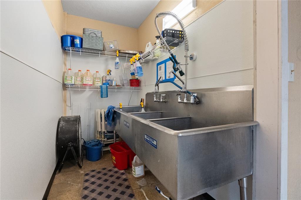 A utility room features a three-compartment stainless steel sink with a sprayer and wire shelving — 15601 OLD US HIGHWAY 441, TAVARES, FL