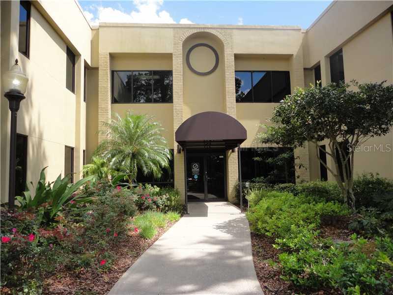 A concrete walkway leads to the entrance of a two-story beige office building with landscaping — 36739 COUNTY ROAD 52 UNIT 203, DADE CITY, FL