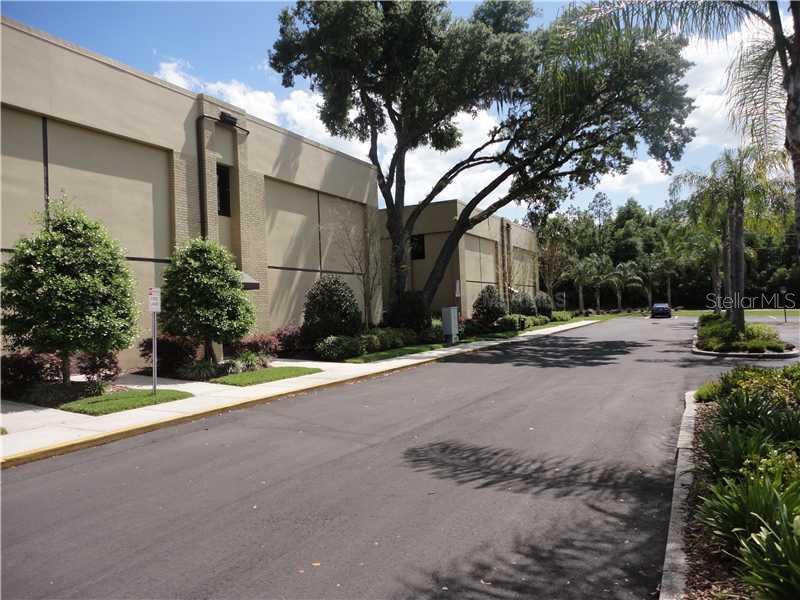 A paved driveway leads past a beige commercial building with landscaping and mature trees — 36739 COUNTY ROAD 52 UNIT 203, DADE CITY, FL