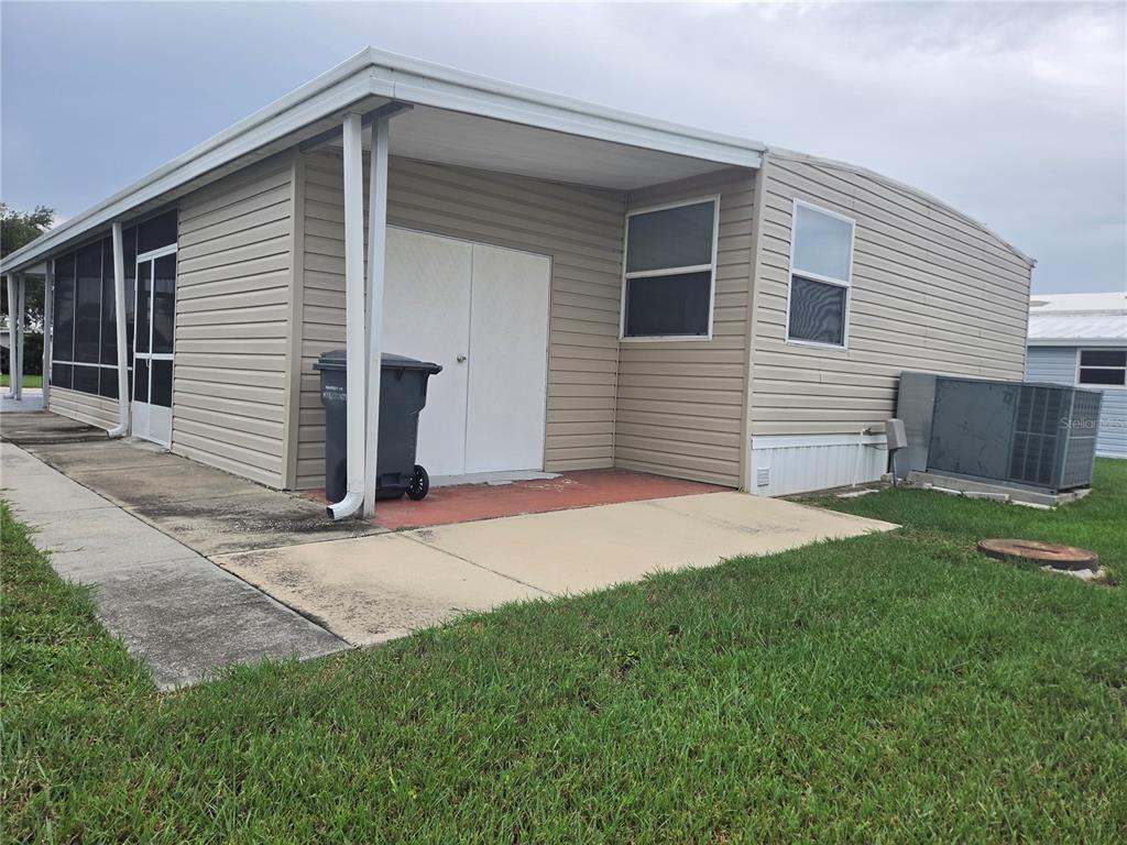 A beige mobile home features a screened-in porch, a storage shed, and a concrete patio — 628 LAKESIDE RANCH LANE, WINTER HAVEN, FL