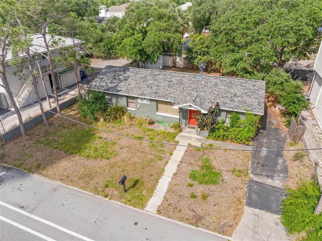 An empty room features light gray walls, tiled flooring, two windows with blinds, and corner shelving — 110 N LINCOLN AVENUE, TAMPA, FL