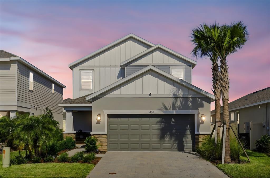 A two-story suburban house with a gray garage, stone accents, and a palm tree — 5268 KILDARE PLACE, ST CLOUD, FL