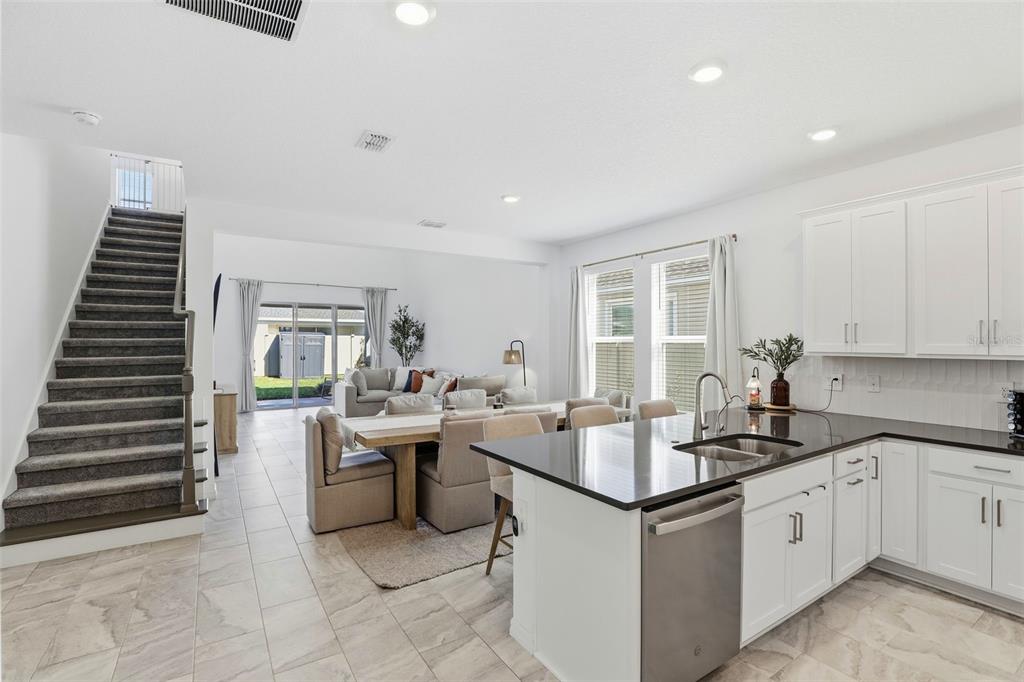 A kitchen with dark countertops and white cabinets overlooks a dining area and living room — 5268 KILDARE PLACE, ST CLOUD, FL