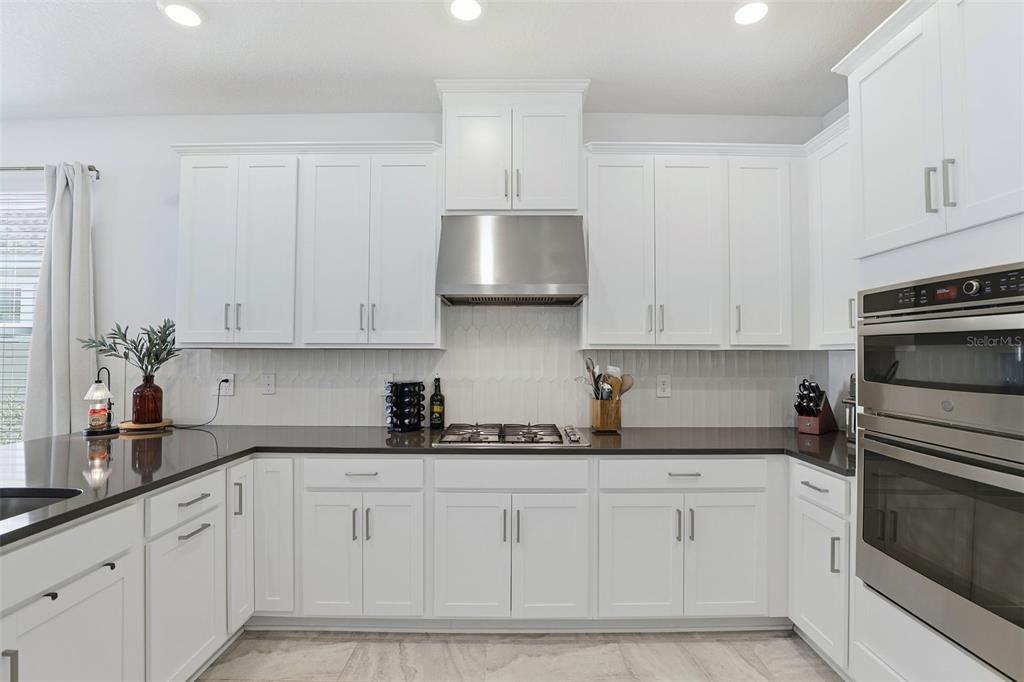 A kitchen with white cabinets, stainless steel appliances, and dark countertops — 5268 KILDARE PLACE, ST CLOUD, FL