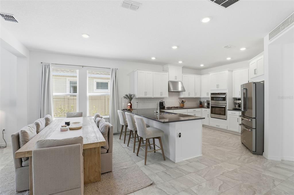 A bright kitchen features white cabinets, a dark island countertop, and an adjacent dining area — 5268 KILDARE PLACE, ST CLOUD, FL