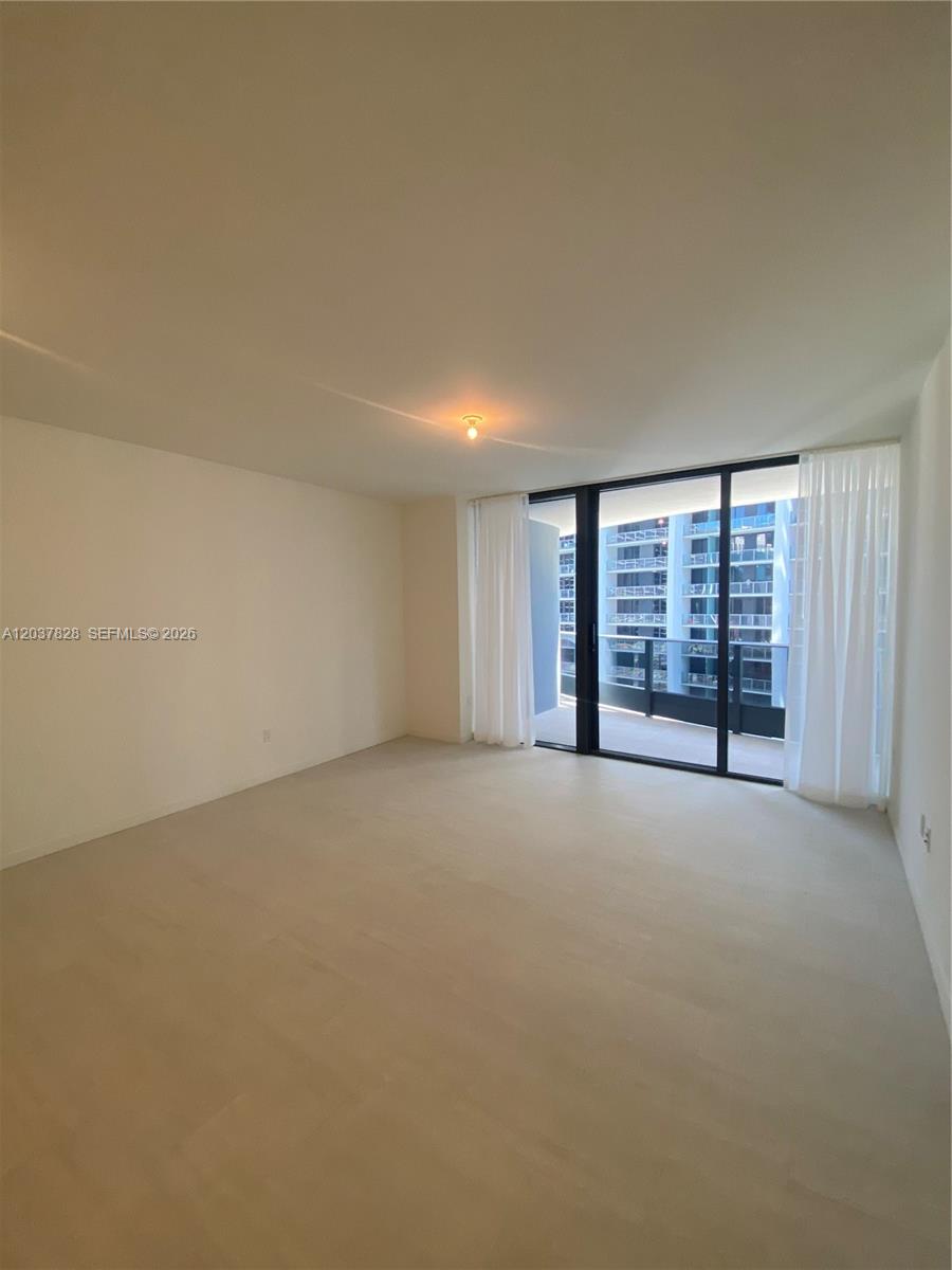 An empty room features light-colored flooring, white walls, and a sliding glass door to a balcony — 1000 Brickell Plaza # 2007, Miami FL 33131, MIAMI, FL