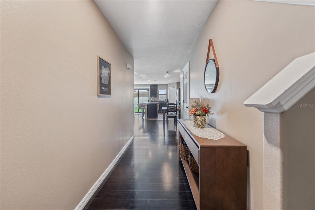 A hallway with dark wood floors leads toward a kitchen with a breakfast bar — 2220 WINDSOR LAKE CIRCLE, SANFORD, FL