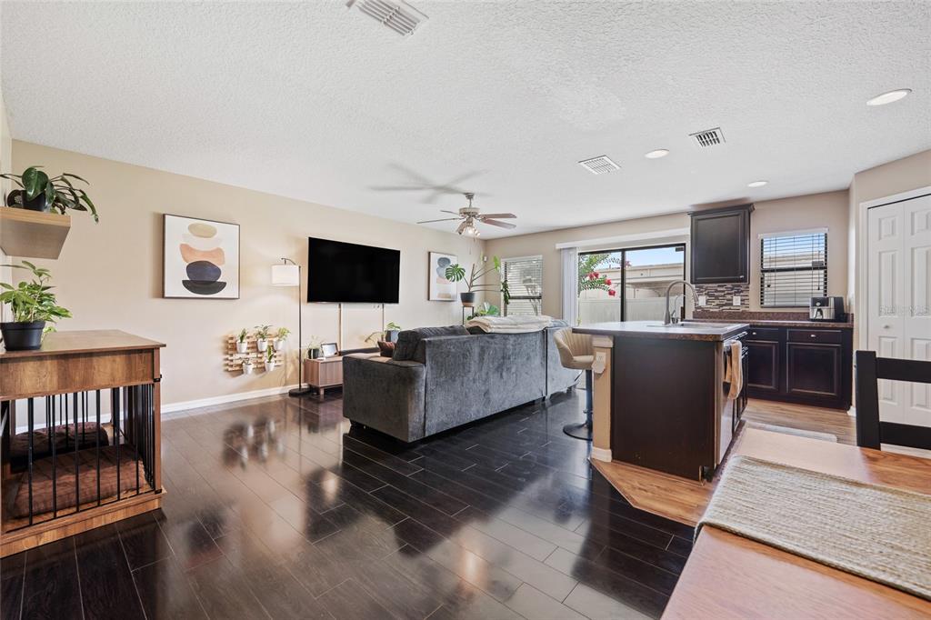 An open-concept living room and kitchen feature dark wood flooring and a gray sectional sofa — 2220 WINDSOR LAKE CIRCLE, SANFORD, FL
