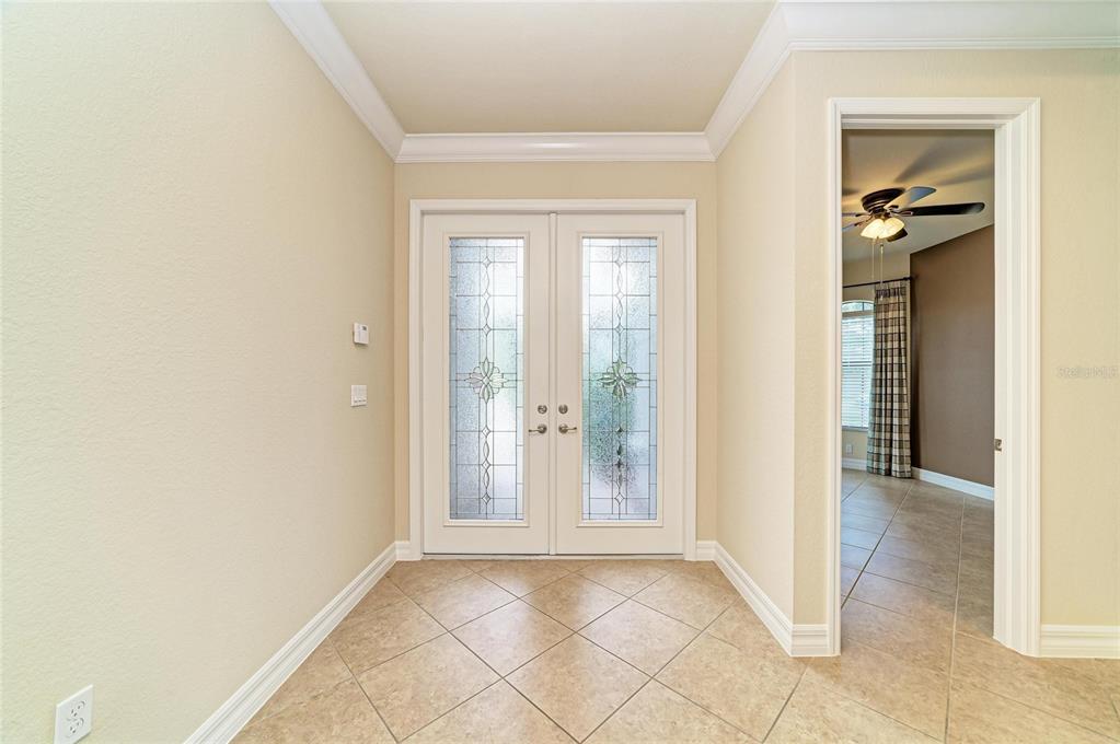 An entryway features beige tile flooring, crown molding, and double glass-paneled front doors — 3701 PLEASANT SPRINGS DRIVE, NAPLES, FL