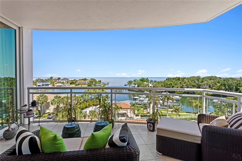A balcony with wicker furniture overlooks a waterway, boat docks, and a distant horizon — 1325 SNELL ISLE BOULEVARD NE UNIT 507, ST PETERSBURG, FL