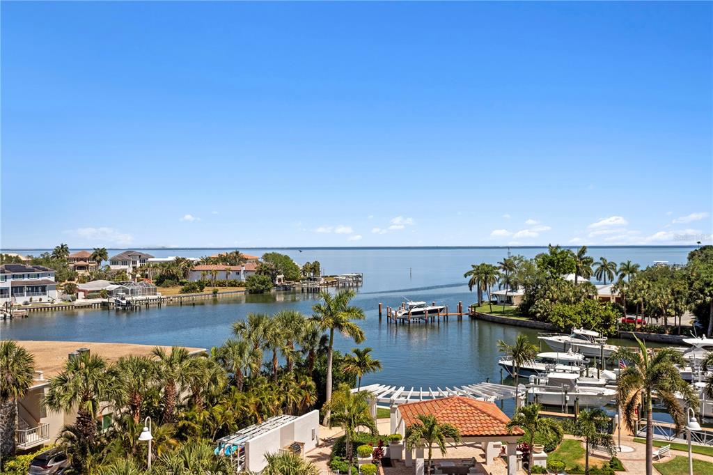 An elevated view of a waterfront canal with boats, palm trees, and a distant bay — 1325 SNELL ISLE BOULEVARD NE UNIT 507, ST PETERSBURG, FL