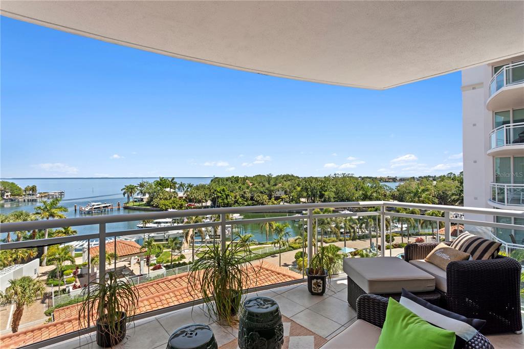 A balcony with outdoor furniture overlooks a waterfront view with boats and palm trees — 1325 SNELL ISLE BOULEVARD NE UNIT 507, ST PETERSBURG, FL