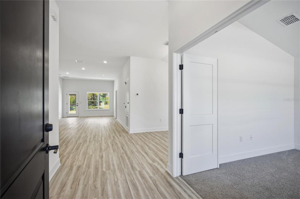 An interior view shows a carpeted room with a white door opening to a living area — 16794 NW 178TH TERRACE, ALACHUA, FL