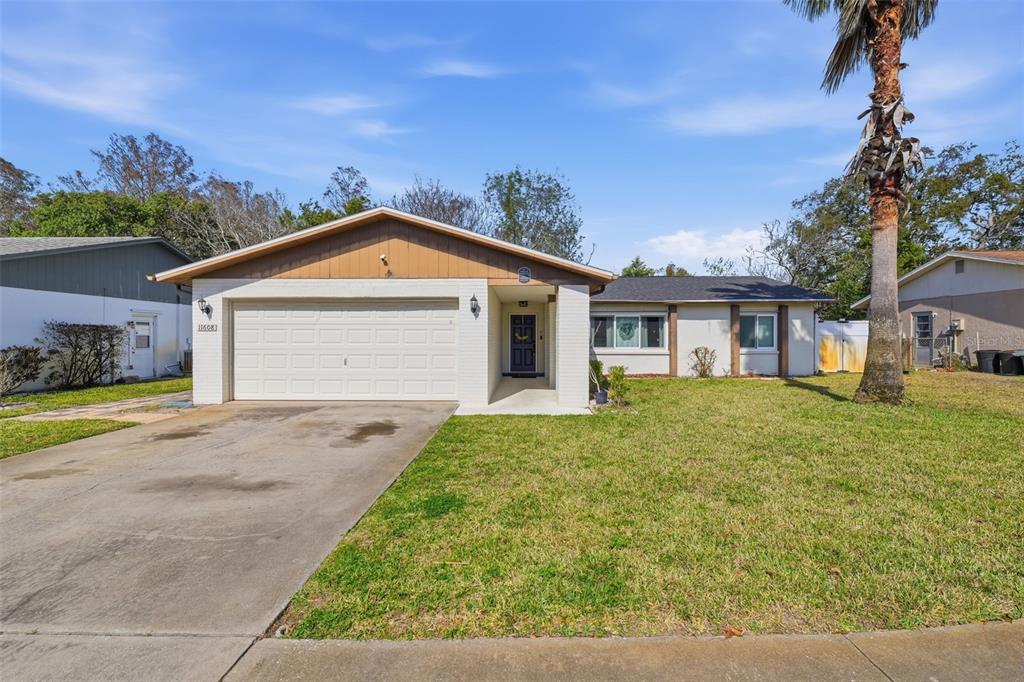 A single-story house with a white brick facade, a two-car garage, and a palm tree — 11608 FOX RUN, PORT RICHEY, FL
