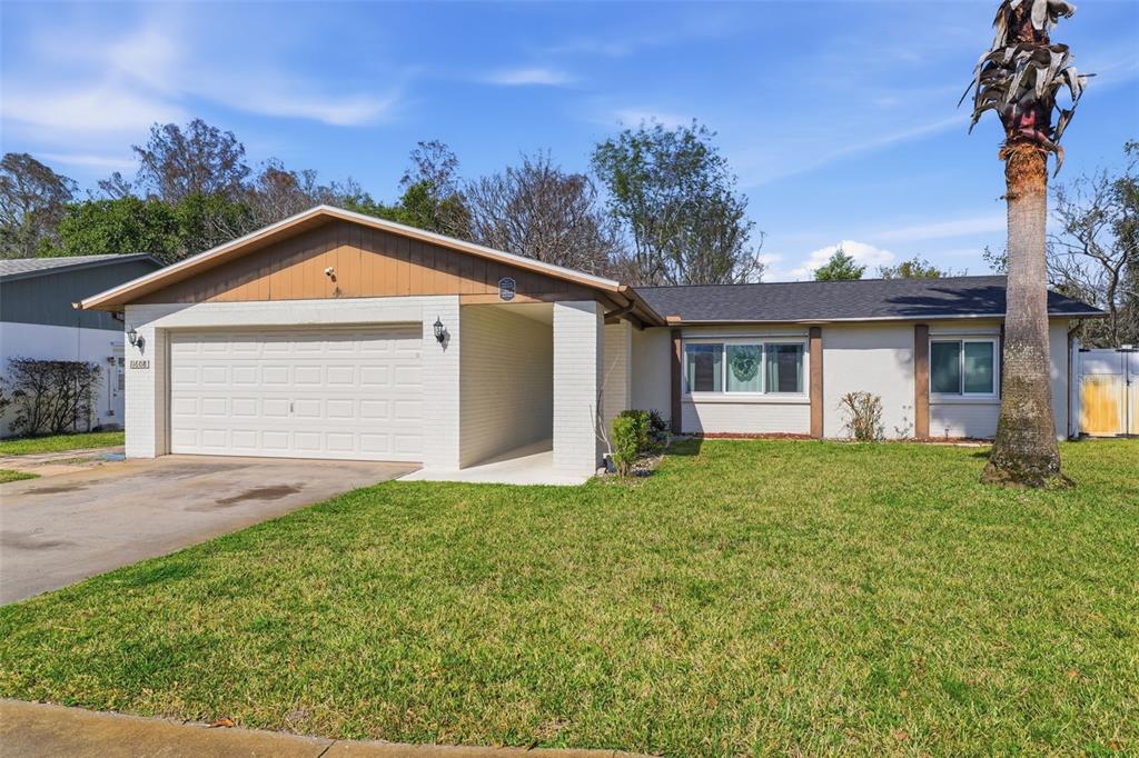 A single-story house with a white brick facade, a two-car garage, and a palm tree — 11608 FOX RUN, PORT RICHEY, FL