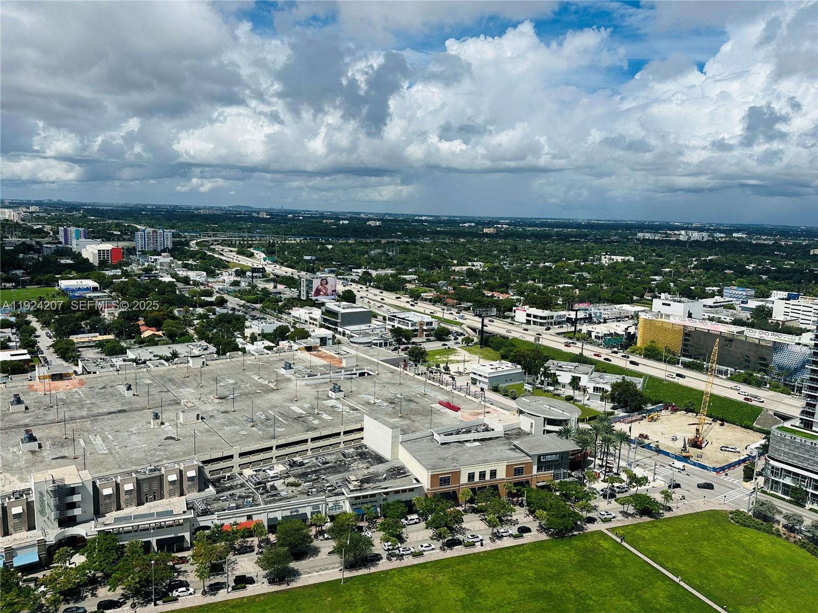 An aerial view shows a large parking structure, surrounding commercial buildings, and a nearby highway — 121 NE 34th St # 3014, Miami FL 33137, MIAMI, FL