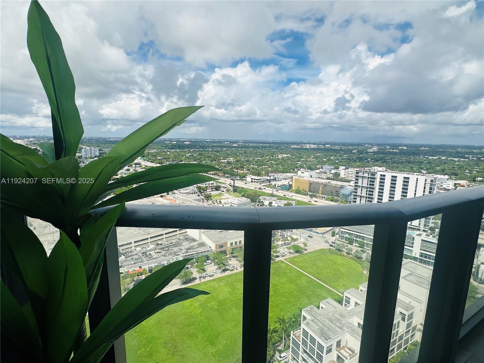 A high-angle view from a balcony overlooking a city park and urban landscape — 121 NE 34th St # 3014, Miami FL 33137, MIAMI, FL