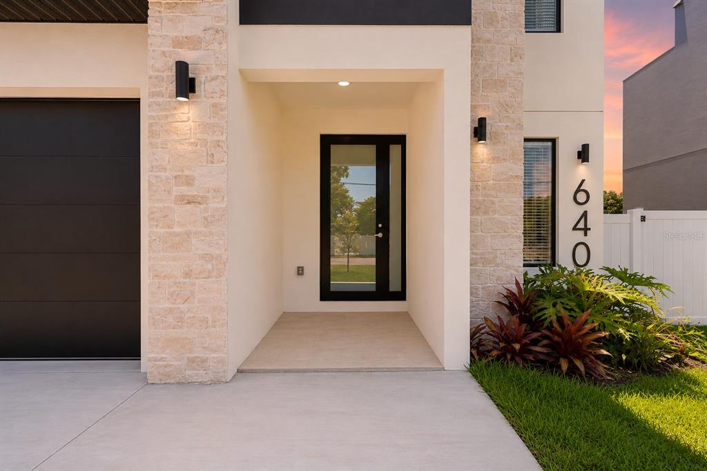 The exterior of a modern home features a stone facade, a black front door, and address numbers — 6403 S RICHARD AVENUE, TAMPA, FL