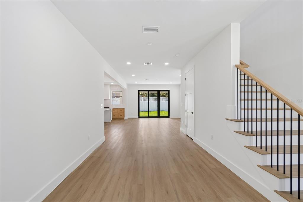 A bright, open-concept living area features light wood flooring, white walls, and a modern staircase — 6403 S RICHARD AVENUE, TAMPA, FL