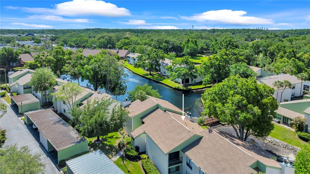 An aerial view shows a multi-story apartment complex with a canal and surrounding trees — 4114 PINELAKE LANE UNIT 202, TAMPA, FL