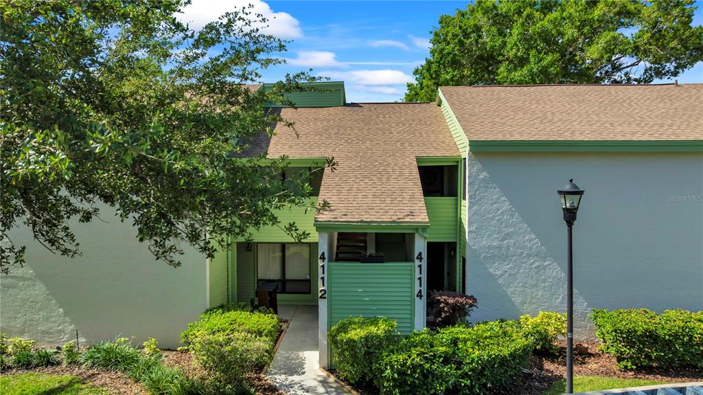 A two-story building exterior features light green siding, a shingled roof, and a central walkway — 4114 PINELAKE LANE UNIT 202, TAMPA, FL