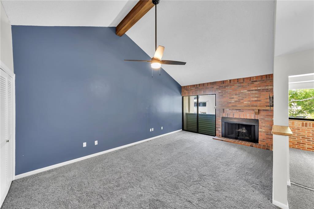 A living room features a vaulted ceiling, a blue accent wall, and a brick fireplace — 4114 PINELAKE LANE UNIT 202, TAMPA, FL