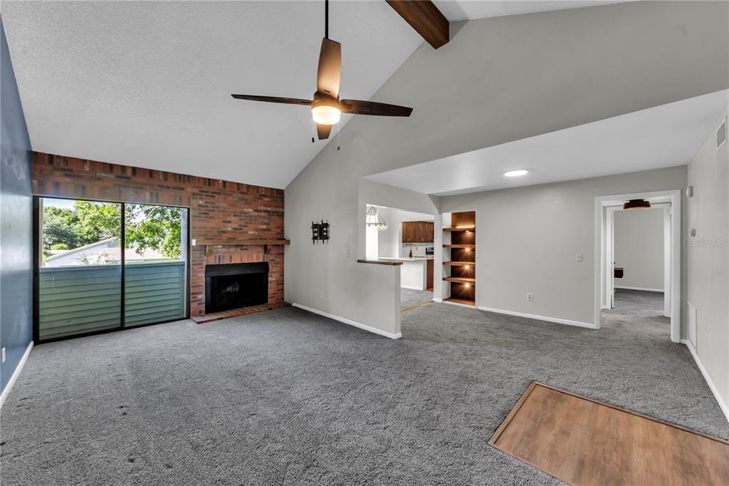 A living room features a brick fireplace, vaulted ceiling, ceiling fan, and carpeted flooring — 4114 PINELAKE LANE UNIT 202, TAMPA, FL