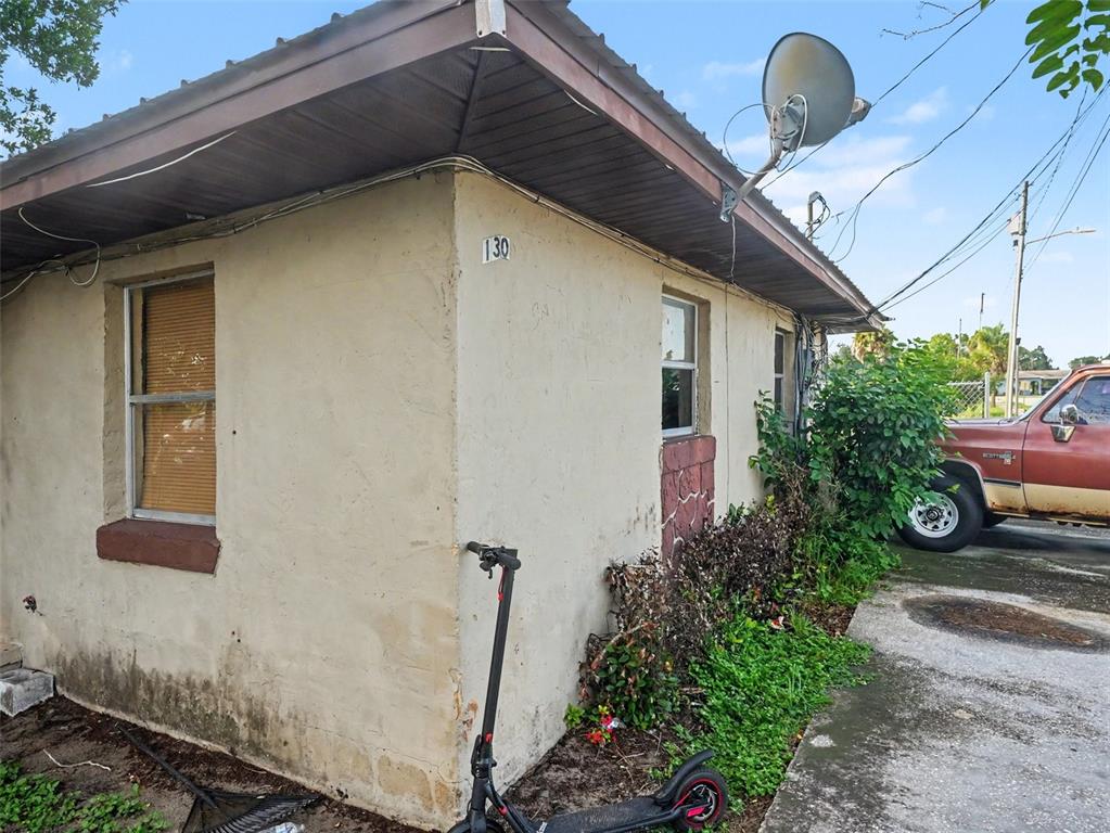 An exterior view of a small, single-story stucco building with a satellite dish and scooter — 130 D STREET UNIT 1,2,3,4, LAKE WALES, FL