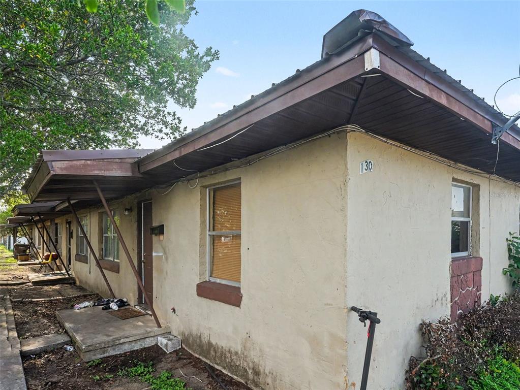 A single-story apartment building exterior with a concrete walkway, brown trim, and a metal roof — 130 D STREET UNIT 1,2,3,4, LAKE WALES, FL