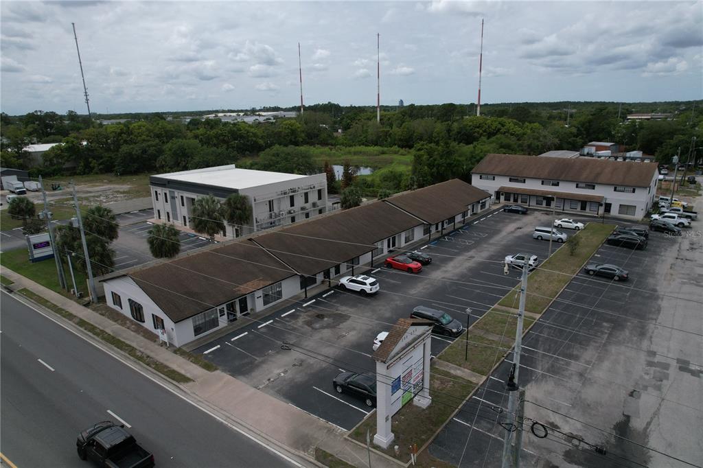 An aerial view shows a commercial building with a parking lot and surrounding landscape — 254 S RONALD REAGAN BOULEVARD UNIT 132, LONGWOOD, FL