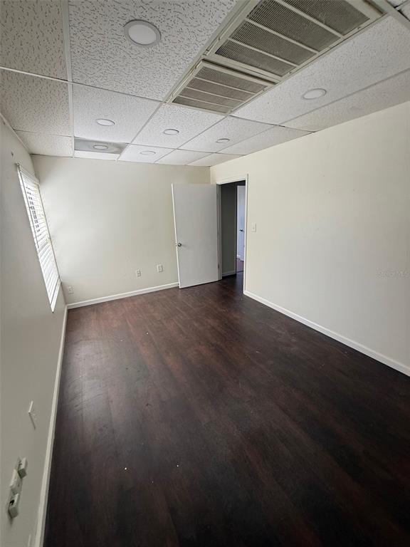 An empty room features dark wood-look flooring, white walls, and a drop ceiling with recessed lighting — 254 S RONALD REAGAN BOULEVARD UNIT 132, LONGWOOD, FL