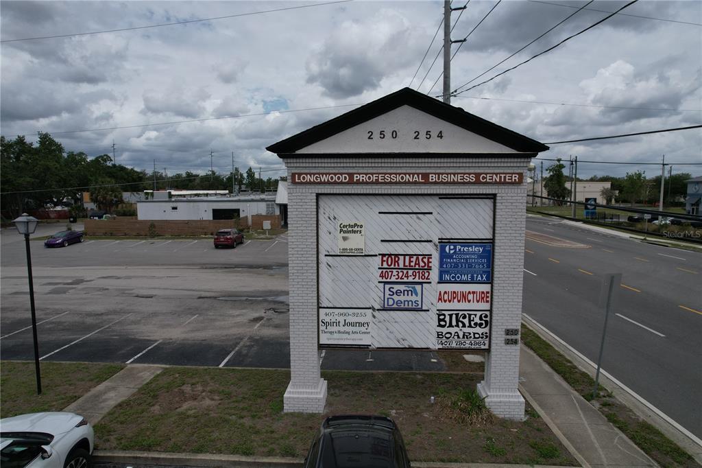 A multi-tenant business center sign stands in a parking lot near a road — 254 S RONALD REAGAN BOULEVARD UNIT 132, LONGWOOD, FL