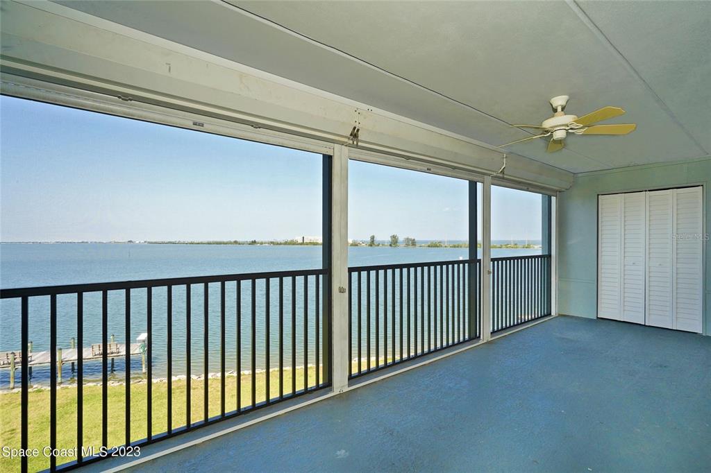A screened-in balcony features a blue floor, a ceiling fan, and a waterfront view — 3799 S BANANA RIVER BOULEVARD UNIT 823, COCOA BEACH, FL