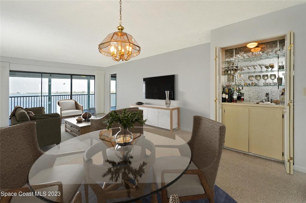 A dining area with a glass table and a living room featuring a wet bar — 3799 S BANANA RIVER BOULEVARD UNIT 823, COCOA BEACH, FL