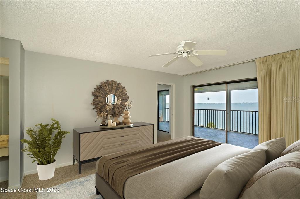 A bedroom features a bed, a wooden dresser, a ceiling fan, and a balcony view — 3799 S BANANA RIVER BOULEVARD UNIT 823, COCOA BEACH, FL
