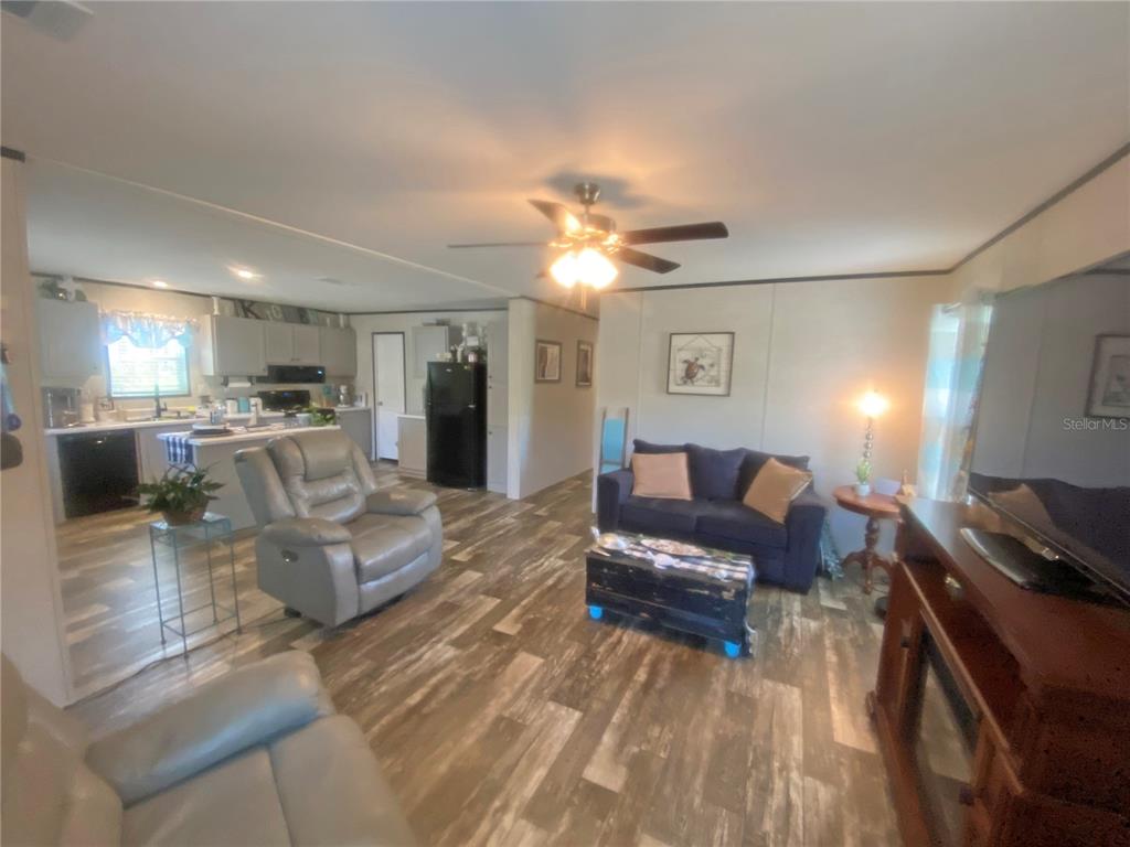 An open-concept living room and kitchen feature wood-look flooring, a ceiling fan, and neutral walls — 203 SW 5TH AVENUE, PALATKA, FL