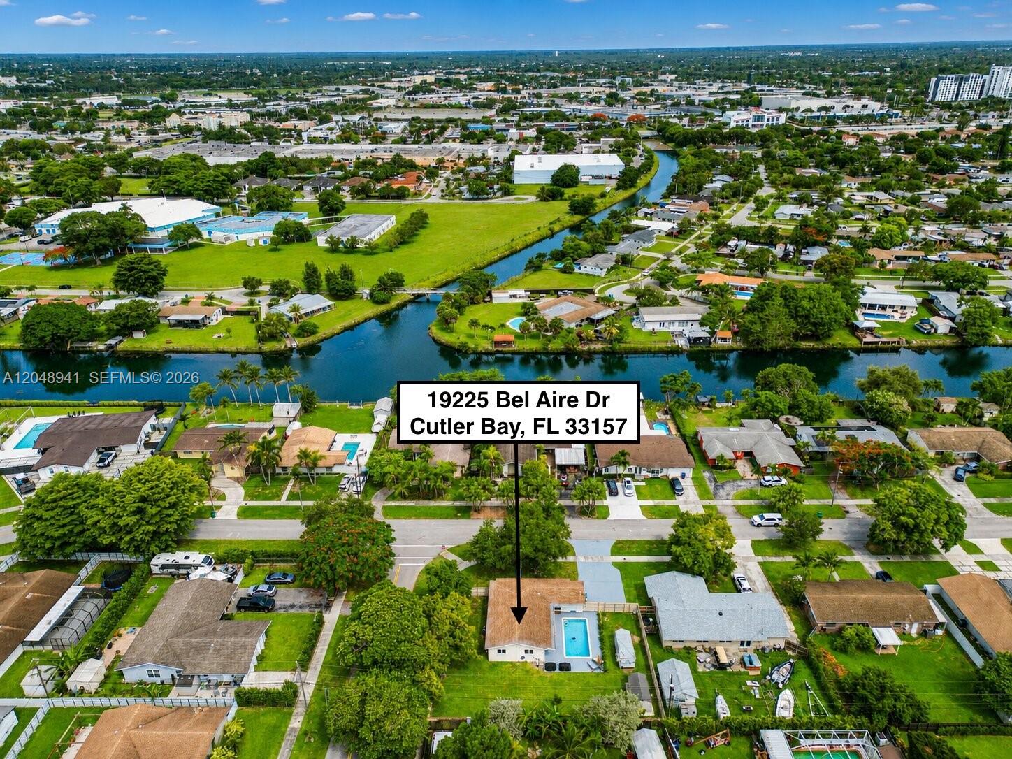 An aerial view shows a residential house with a swimming pool near a canal — 19225 Bel Aire Dr, Cutler Bay FL 33157, CUTLER BAY, FL