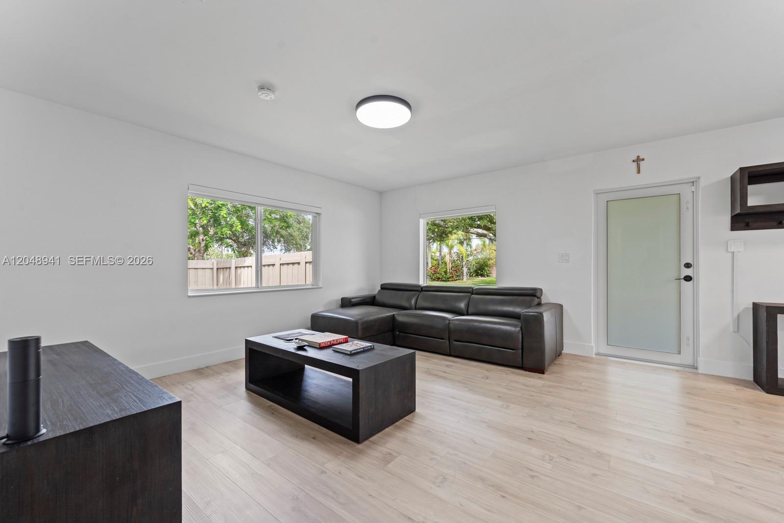 A living room features a dark leather sectional, a matching coffee table, and light wood flooring — 19225 Bel Aire Dr, Cutler Bay FL 33157, CUTLER BAY, FL
