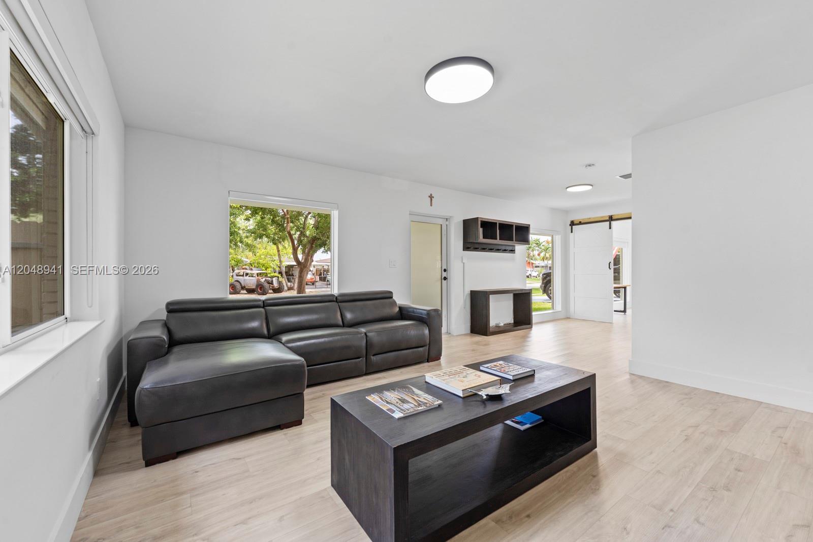 A living room features a dark leather sectional, a matching coffee table, and light flooring — 19225 Bel Aire Dr, Cutler Bay FL 33157, CUTLER BAY, FL