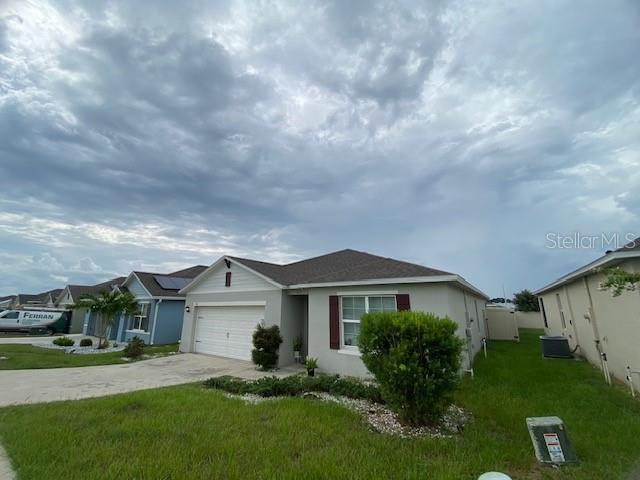 A single-story suburban house with a white garage door and a green lawn — 963 SERCHIO STREET, HAINES CITY, FL