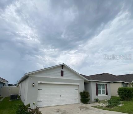 A single-story house with a two-car garage and a light gray exterior under a cloudy sky — 963 SERCHIO STREET, HAINES CITY, FL