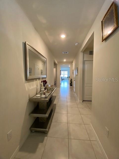 A long hallway with light tile flooring, a console table, and a mirror on the wall — 963 SERCHIO STREET, HAINES CITY, FL