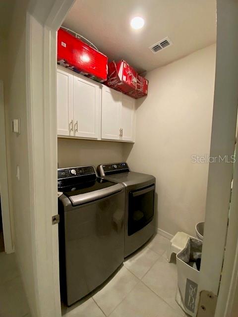 A laundry room features grey appliances, white upper cabinets, and light-colored tile flooring — 963 SERCHIO STREET, HAINES CITY, FL