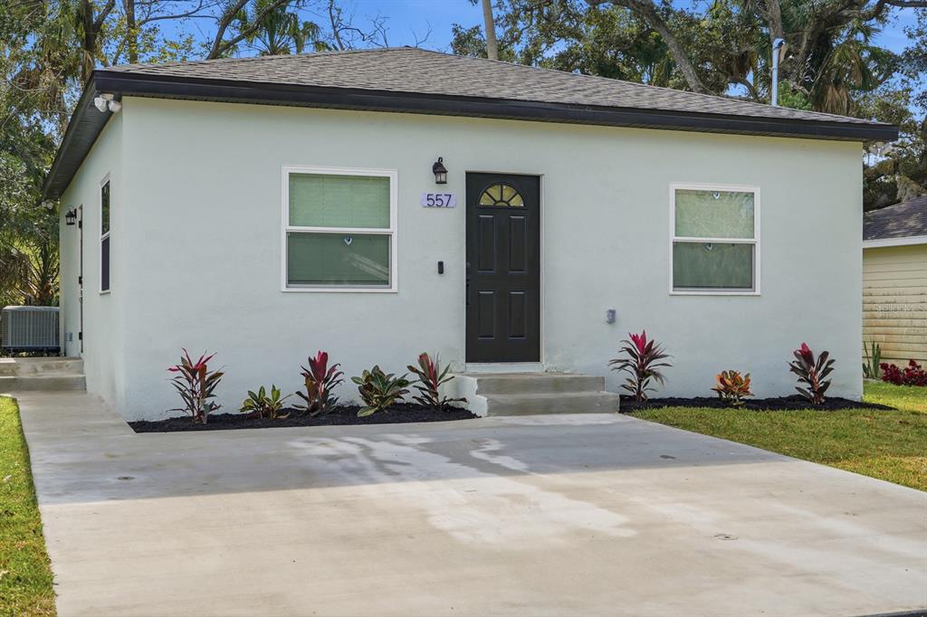A single-story house with light green stucco walls, a dark front door, and concrete driveway — 557 LIVE OAK AVENUE, DAYTONA BEACH, FL