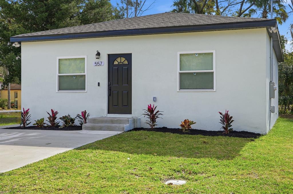 A single-story house with white stucco siding, a dark front door, and a concrete driveway — 557 LIVE OAK AVENUE, DAYTONA BEACH, FL