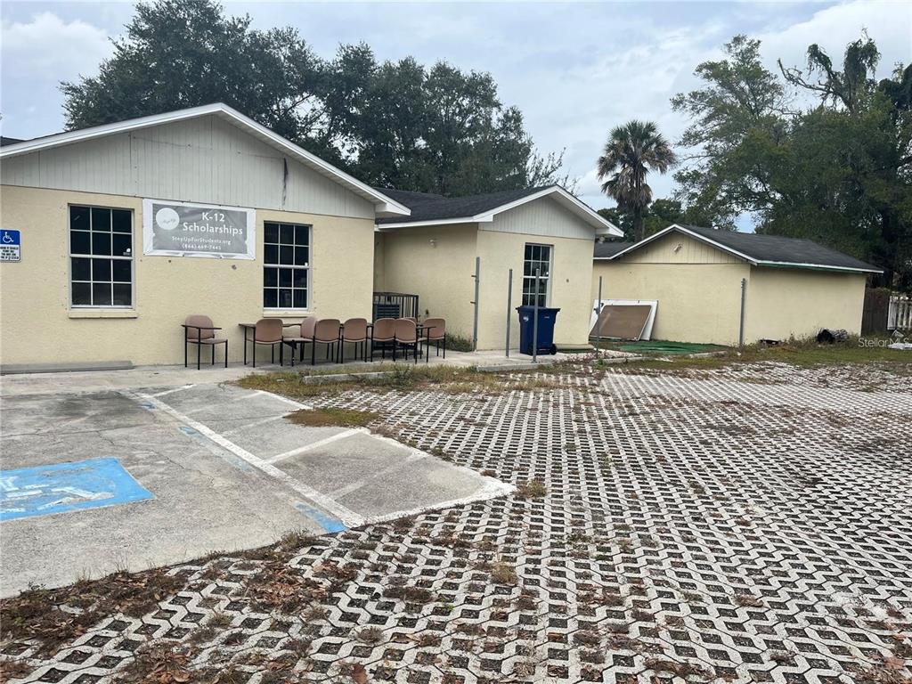 An exterior view of a single-story building with a paved parking lot and outdoor seating — 2222 E DR MARTIN LUTHER KING JR BOULEVARD, TAMPA, FL